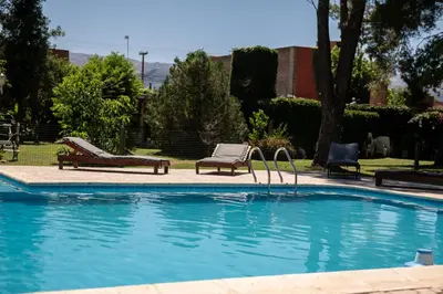 a swimming pool with two chairs and a bench next to it at Los Robles in Villa Cura Brochero