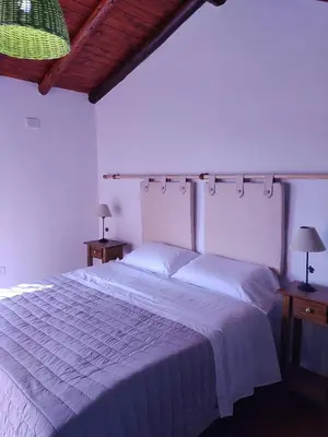 a bedroom with a large white bed with two lamps at Cabañas La Ramadita in La Ramada