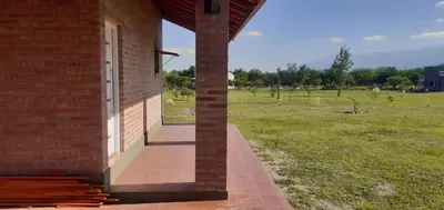 a brick building with a door and a field of grass at Cabañas Mini Tinkuy in Cortaderas
