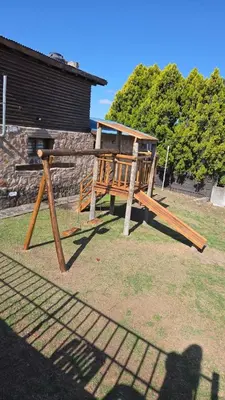 a shadow of a person taking a picture of a wooden playground at Cabañas Postal de la Villa in Villa Carlos Paz