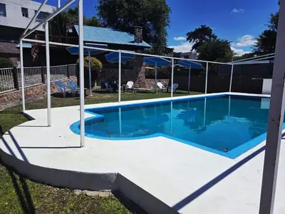 a swimming pool with blue water in a yard at Cabañas Postal de la Villa in Villa Carlos Paz
