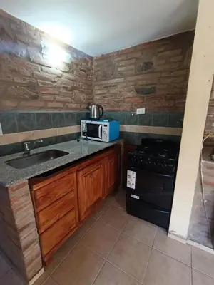 a small kitchen with a sink and a stove at Cabañas Postal de la Villa in Villa Carlos Paz