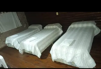 two beds with white sheets in a room at Cabañas Postal de la Villa in Villa Carlos Paz