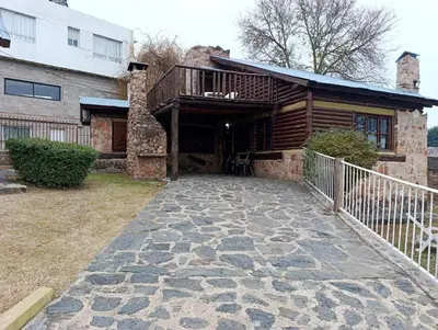 a house with a porch and a balcony on it at Cabañas Postal de la Villa in Villa Carlos Paz