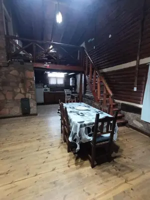 a dining room with a table and a staircase at Cabañas Postal de la Villa in Villa Carlos Paz