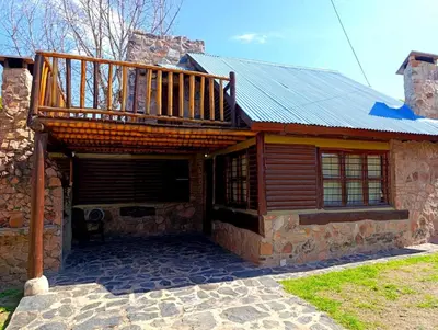 a house with a wooden deck on top of it at Cabañas Postal de la Villa in Villa Carlos Paz