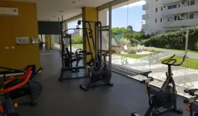 a room with a gym with chairs and a large window at Departamento 1 dormitorio con pileta gimnasio y sala de juegos in Cordoba