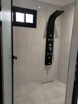 a bathroom with a shower with a black object on the wall at Tres Deseos in Villa Cura Brochero