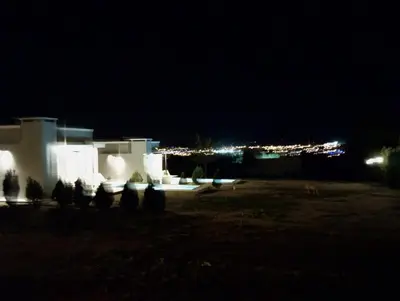 a night view of a building with a city in the background at Tres Deseos in Villa Cura Brochero
