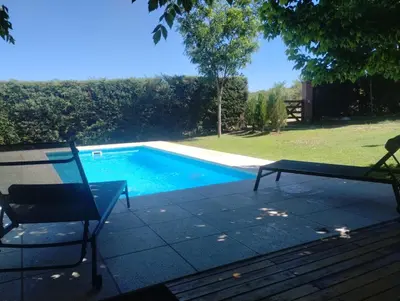 a swimming pool with a chair and a bench on a patio at Tres Deseos in Villa Cura Brochero