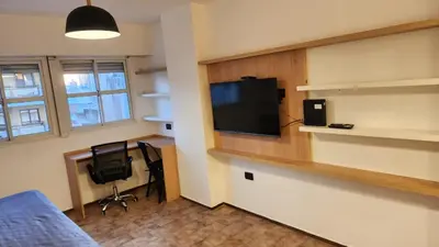 a room with a bed and a desk with a television at Av General Paz 418 Centro Parking economico in Cordoba