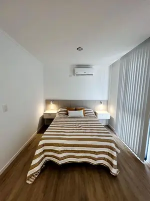 a large bed in a room with a striped blanket on it at Miralejos 17 in Villa Carlos Paz