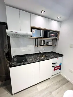 a white kitchen with a sink and a microwave at Miralejos 17 in Villa Carlos Paz