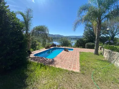 a swimming pool in a yard with a view of the water at Casa Panoramica Maria Ines in Villa Carlos Paz