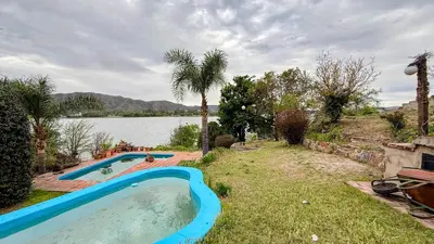 a swimming pool in a yard next to a lake at Casa Panoramica Maria Ines in Villa Carlos Paz