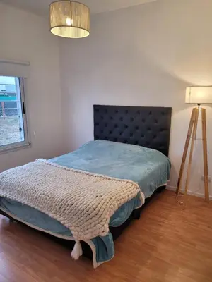 a bedroom with a bed with a black headboard and a lamp at Tu Nuevo Hogar in Alta Gracia