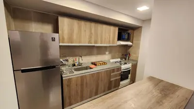 a kitchen with a stainless steel refrigerator and wooden cabinets at Torre GNI Cofico in Cordoba