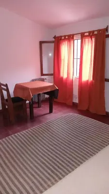 a living room with a table and a red curtain at CASONA Malva del Rio in Villa Carlos Paz