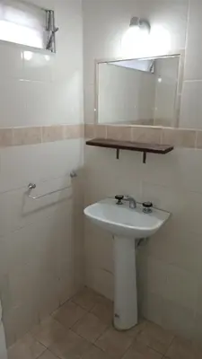 a white bathroom with a sink and a mirror at CASONA Malva del Rio in Villa Carlos Paz