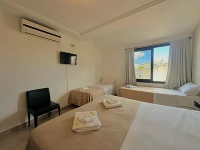 a hotel room with two beds and a window at Hotel Toulon in Villa Carlos Paz