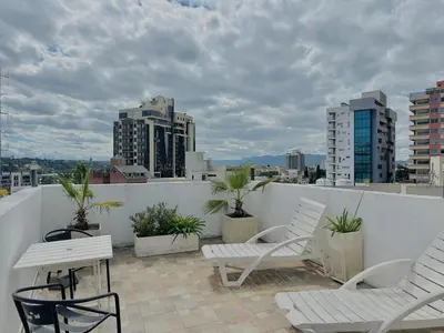 a balcony with white chairs and tables and buildings at Hotel Toulon in Villa Carlos Paz