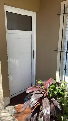 a white garage door with a plant in front of it at Cabaña Hakuna matata in Santa Rosa de Calamuchita