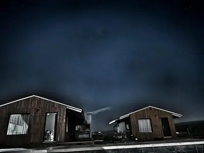two small wooden buildings under a dark sky at algo con sierras in Villa Yacanto