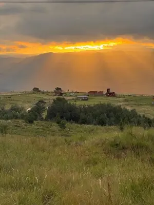 a view of a field with the sun setting behind a mountain at algo con sierras in Villa Yacanto