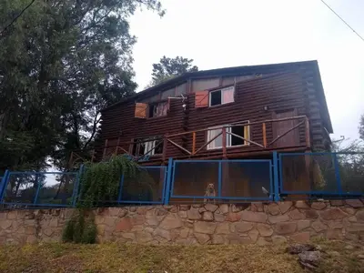 a wooden house on top of a stone wall at Cabañas aguaribay in Villa Parque Siquiman
