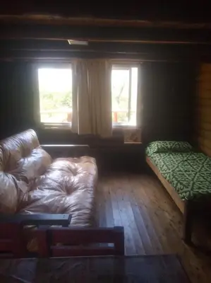 a living room with a couch and a bed and two windows at Cabañas aguaribay in Villa Parque Siquiman