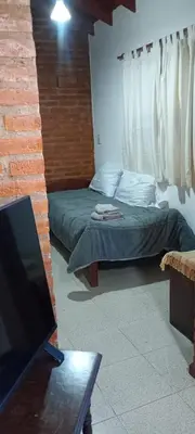 a bedroom with two beds and a flat screen tv at Un rincón en el centro in Merlo