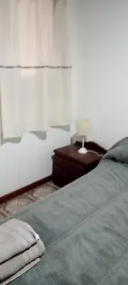 a bedroom with a bed and a table with a lamp at Un rincón en el centro in Merlo