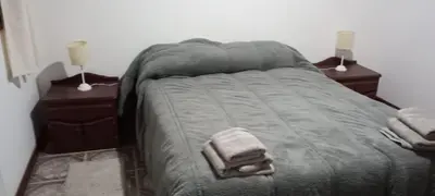 a bed in a bedroom with two night stands and two lamps at Un rincón en el centro in Merlo