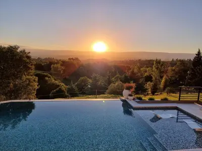 a woman sitting on the edge of a swimming pool watching the sunset at Postal de América in Villa Ciudad de America