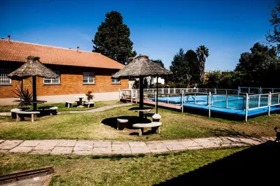 a pool with benches and umbrellas next to a building at Clima Sol in Merlo
