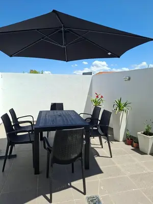 a table and chairs with an umbrella on a patio at Departamento Villa 5 in Villa Carlos Paz
