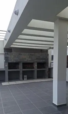 a building with a stone wall and a white roof at Departamento Villa 5 in Villa Carlos Paz