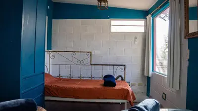 a small bedroom with a bed with an orange blanket at Casita Meraki Duplex para 3 personas in Villa Carlos Paz