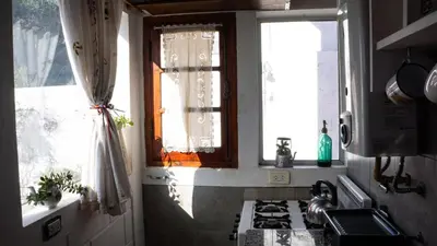 a kitchen with a stove and two windows at Casita Meraki Duplex para 3 personas in Villa Carlos Paz
