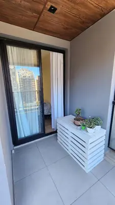 a balcony with two potted plants and a large window at Obispo Salguero 648 - Pleno Nueva Cordoba BY Apartcba in Cordoba