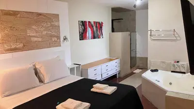 a bedroom with a bed and a tub and a sink at Casa Alta Hotel Boutique & Spa - Solo Adultos in Villa Carlos Paz