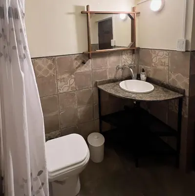 a bathroom with a sink and a toilet and a mirror at Lila Casas de Montaña in La Cumbrecita