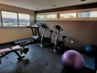 a gym with three exercise bikes in a room with windows at Departamento en Carlos Paz con vistas y céntrico in Villa Carlos Paz