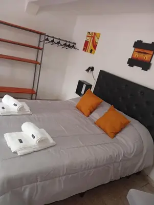 a bed with orange pillows and towels on it at Balcón al Tajamar in Alta Gracia