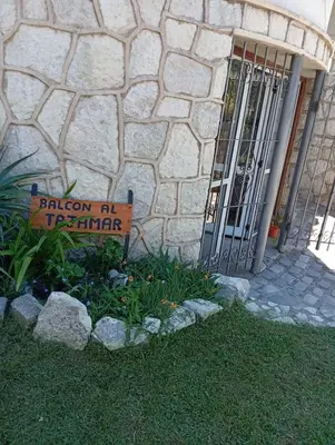 a sign in front of a stone building with a gate at Balcón al Tajamar in Alta Gracia