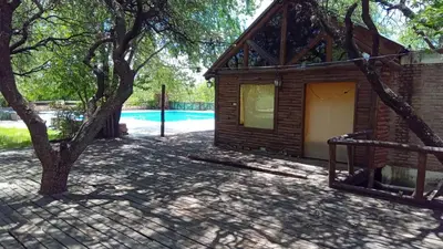 a house with a tree and a swimming pool at APART HOTEl ACUARELA in Mina Clavero