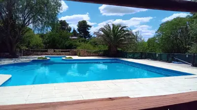 a swimming pool in a backyard with a fence and trees at APART HOTEl ACUARELA in Mina Clavero