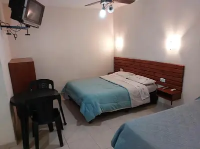 a bedroom with a bed and a desk and a television at APART HOTEl ACUARELA in Mina Clavero