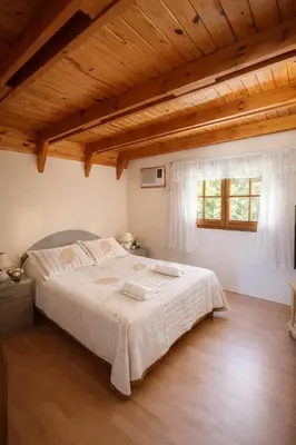 a bedroom with a large bed with a wooden ceiling at Chalet Alpino en las Sierras in Villa del Dique