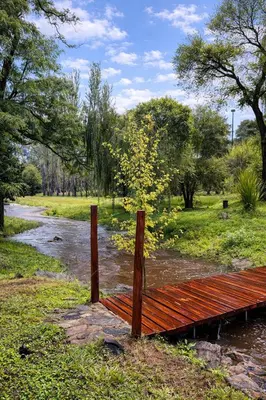 a wooden bridge over a river with at Chalet Alpino en las Sierras in Villa del Dique